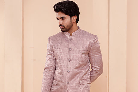 Man wearing a light pink traditional jacket against a beige background
